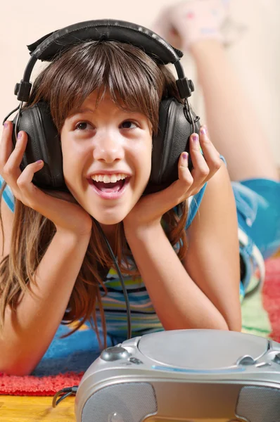 Tienermeisje ligt op de verdieping en luistert naar de muziek — Stockfoto