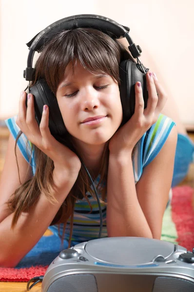 Teenage girl lies on the floor and listens to the music — Stock Photo, Image