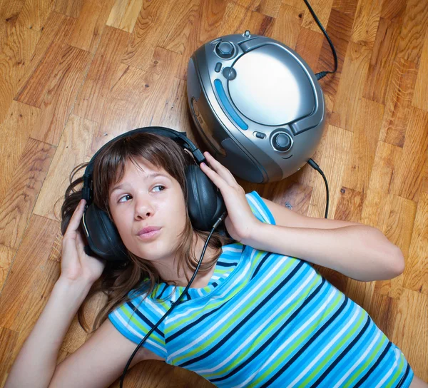 Teenage girl lies on the floor and listens to the music — Stock Photo, Image