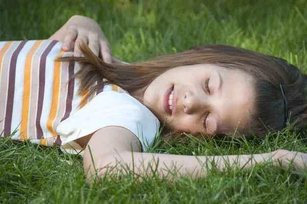 Hübsches junges Mädchen im Teenageralter, das sich auf dem Grasbett ausruht. — Stockfoto