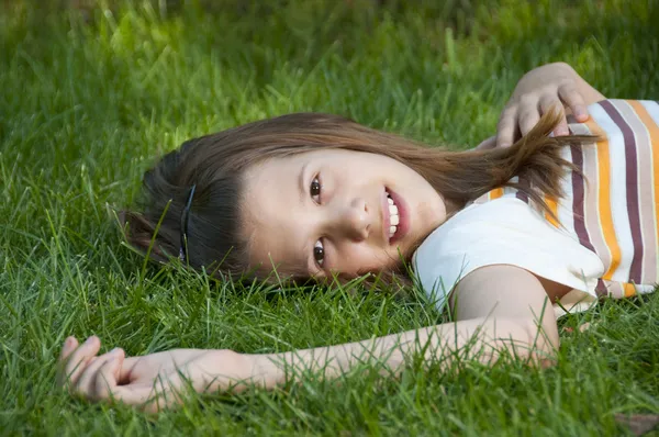 Pretty young teenage girl resting on the bed of grass and smiling. — Stock Photo, Image