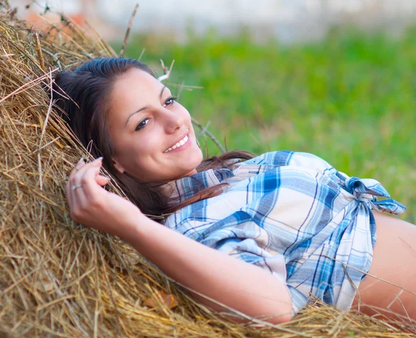 美しい若い女性は干し草と笑顔の山にあります。. — ストック写真