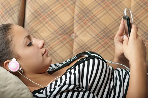 Yatan ise güzel genç kızın cep telefonu müzik dinler — Stok fotoğraf