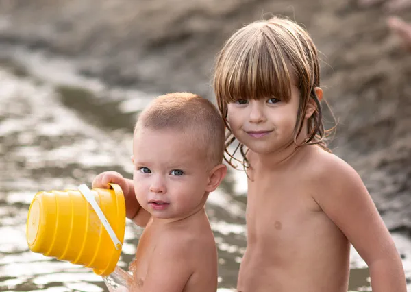 Děti si hrají v písku s plastovým může na horké letní večer. — Stock fotografie