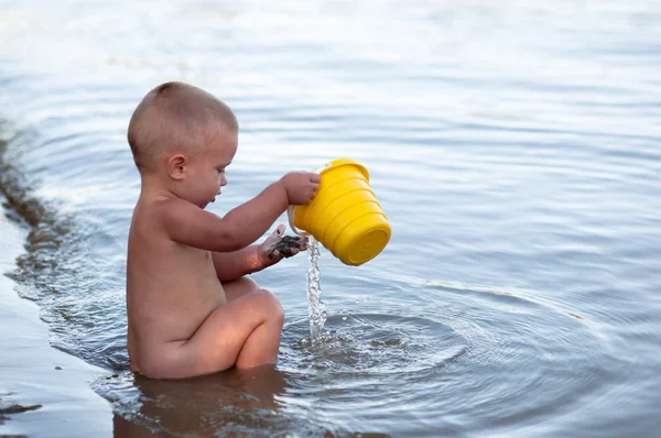 プラスチックが付いている砂で遊んでいる小さな少年は暑い夏の夜に. — ストック写真
