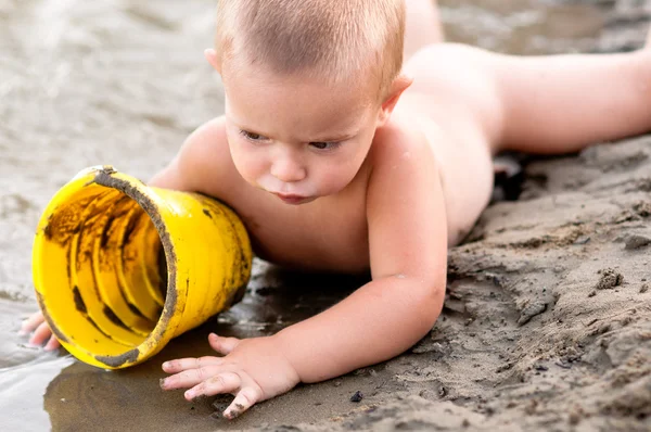 Jongetje spelen in het zand met plastic kan op warme zomeravond. — Stockfoto