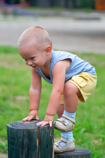 Menino feliz escalando o pilar de madeira no playground ao ar livre . — Fotografia de Stock