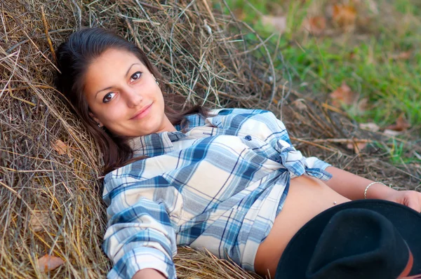 美しい若い女性は干し草と笑顔の山にあります。. — ストック写真
