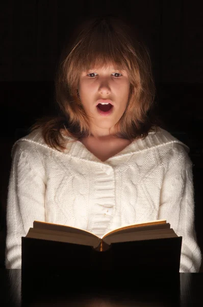 Menina adolescente lendo livro emocionante no escuro . — Fotografia de Stock