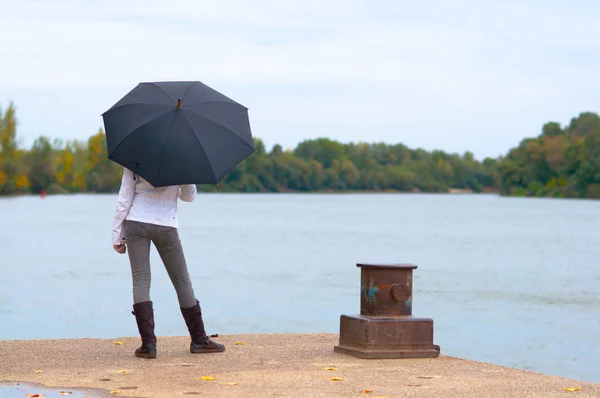 川で待機している若い女性の彼女の手で傘をドックします。 — ストック写真