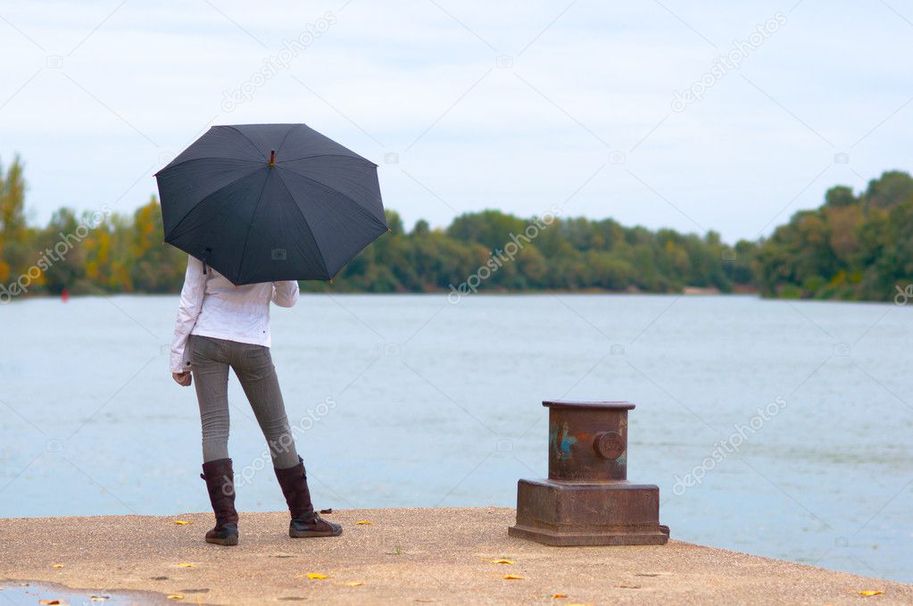 Young women waiting on the river dock with umbrella in her hands