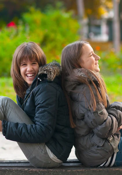 Bardzo nastoletnie dziewczyny, śmiejąc się i żartując siedząc w parku — Zdjęcie stockowe