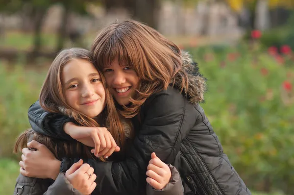 Teenage girls hugging each other in the park on the beautiful autumn day — Stock Photo, Image