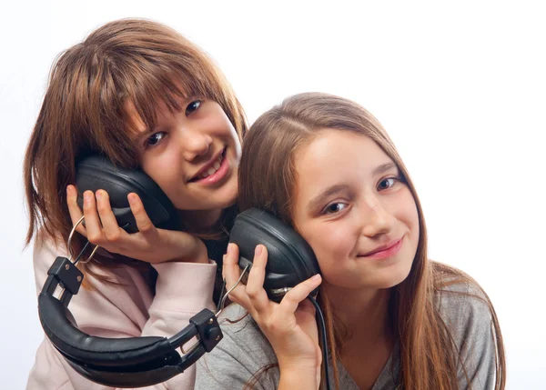 Two teenage girls listen to music together through the headphones — Stock Photo, Image