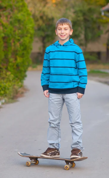 Teenage skateboarder glimlachen terwijl staande op de skateboard buiten — Stockfoto