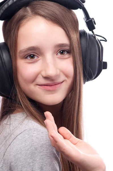 Beautiful teenage girl listens to music through the headphones — Stock Photo, Image