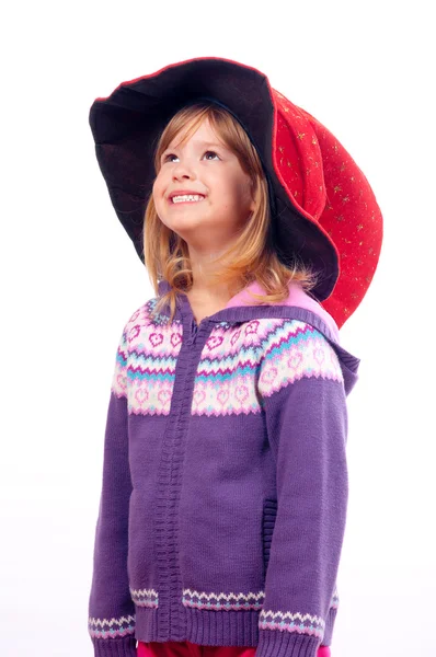 Cute little smiling girl with wizards hat on her head looking up — Stock Photo, Image