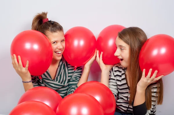 Guapas adolescentes jugando con globos rojos — Foto de Stock