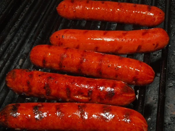 Uma fileira de cinco cachorros-quentes em uma churrasqueira — Fotografia de Stock