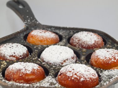 pudra şekeri ile yeni pişirilmiş aebelskivers bir pan