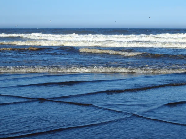 Onde oceaniche che si infrangono sulla riva in un giorno limpido e soleggiato — Foto Stock