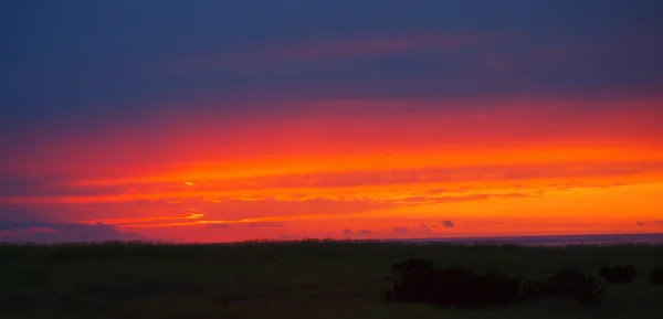 Jasny czerwony zachmurzony zachód słońca za oceanem — Zdjęcie stockowe