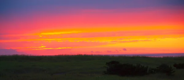 Parlak kırmızı bulutlu günbatımı okyanus ötesinde — Stok fotoğraf