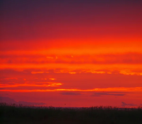 Leuchtend rot bewölkt Sonnenuntergang jenseits des Ozeans — Stockfoto