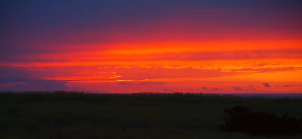 Яскраві червоні хмарно захід сонця поза океану — стокове фото