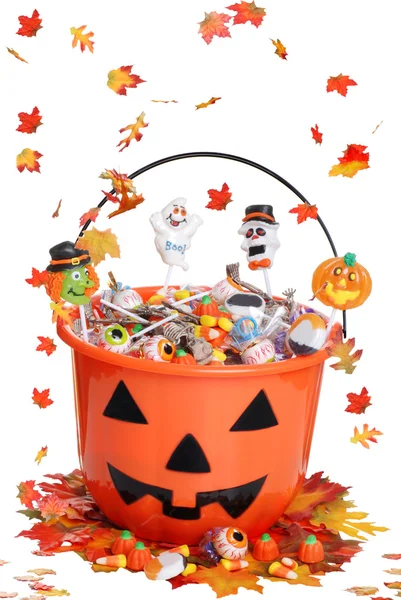 Cubo de calabaza de Halloween con dulces y hojas que caen —  Fotos de Stock