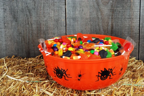 Миска з цукерок Хеллоуїна на соломі — стокове фото