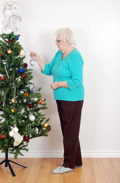 Äldre kvinna dekorera hennes julgran — Stockfoto