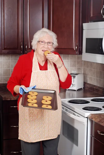 Donna anziana mangiare biscotti freschi — Foto Stock