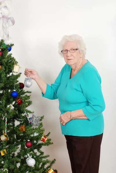 Seniorin hängt Weihnachtsschmuck auf — Stockfoto