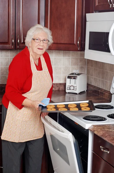 Taze pişmiş kurabiye tepsisi ile üst düzey kadın — Stok fotoğraf