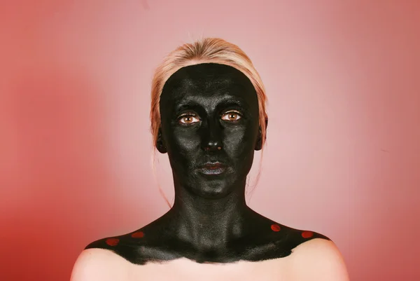 Jovem mulher com rosto pintado de preto — Fotografia de Stock
