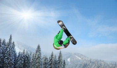 Snowboarder at jump inhigh mountains at sunny day clipart