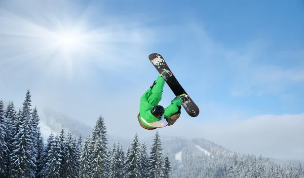 Snowboardåkare hoppar i höga berg på solig dag — Stockfoto