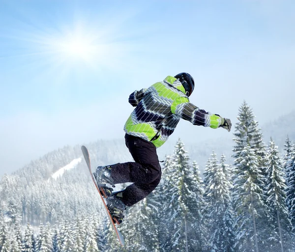 Snowboarder en salto inhigh montañas en día soleado — Foto de Stock