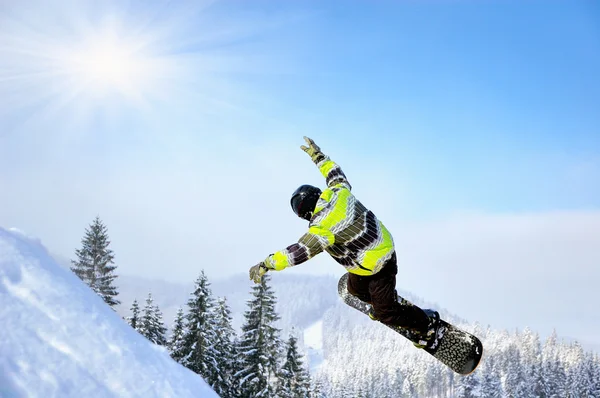 Snowboarder at jump inhigh mountains at sunny day — Stock Photo, Image