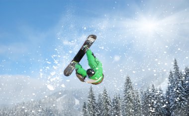 Snowboarder at jump inhigh mountains at sunny day clipart