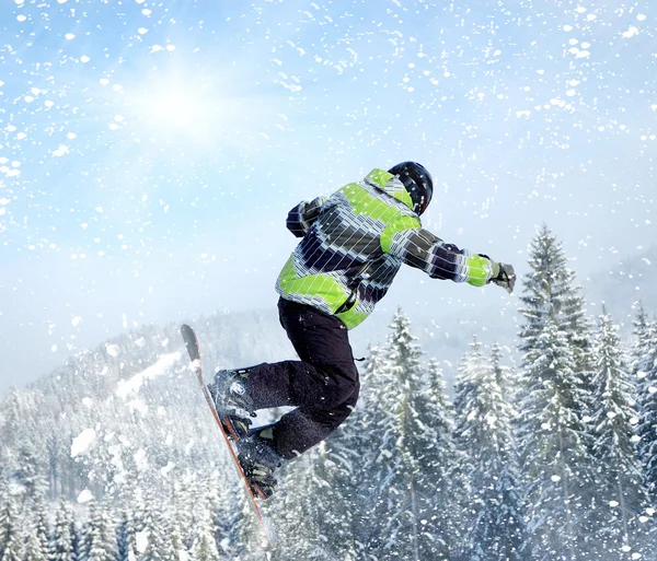 Snowboardista na skok inhigh hory za slunečného dne — Stock fotografie