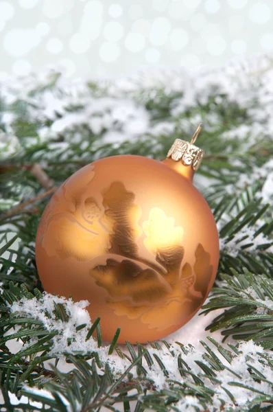 Золотая рождественская безделушка на снегу — стоковое фото