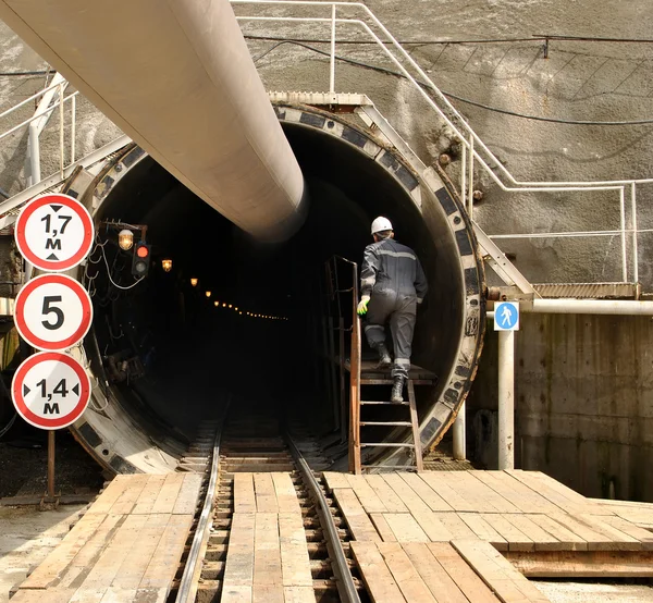 Pracownik budowlany wspina się po schodach w tunelu w budowie — Zdjęcie stockowe