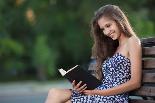 Bella donna bruna si siede sulla panca e libro di lettura sulla città str — Foto Stock