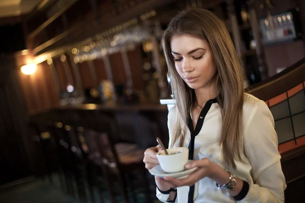 Jovem mulher bonita em um café com uma xícara de café — Fotografia de Stock