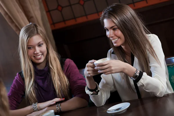 Pretty girl-friends talk and drink coffee in cafe house — Stock Photo, Image