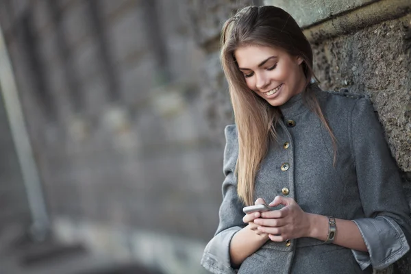 Smiling woman sending sms on the street — Stock Photo, Image