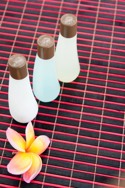 Бутылки шампуня на бамбуковом коврике — стоковое фото