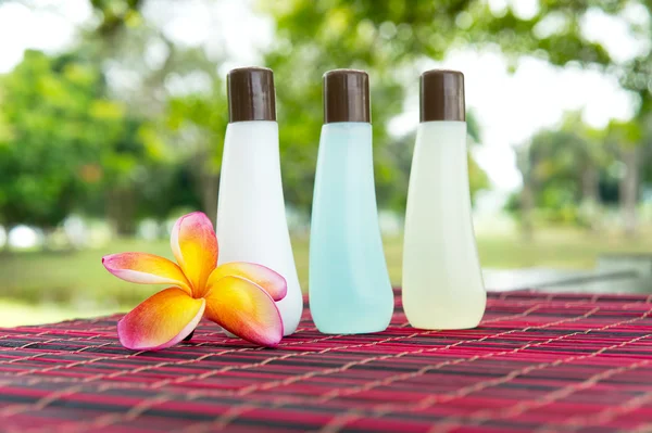 Shampoo-Flaschen und gelbe Frangipani auf Bambusmatte — Stockfoto